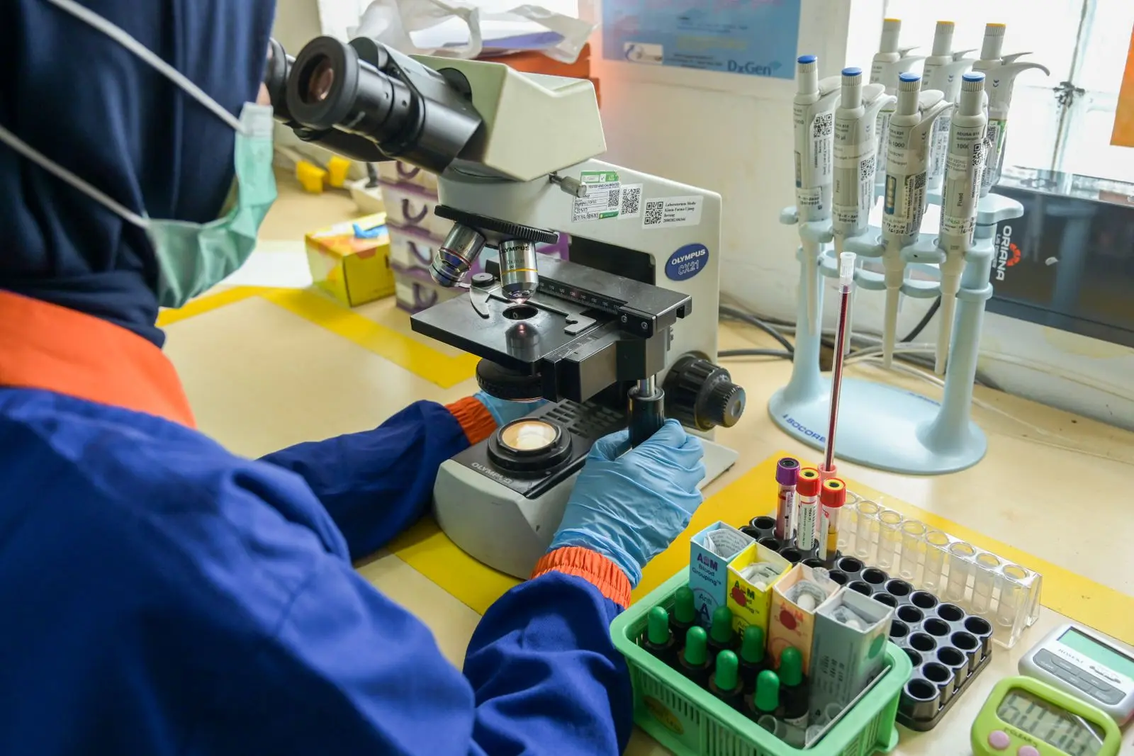 A laboratory technician examines a sample through a microscope in Bandung, Indonesia.