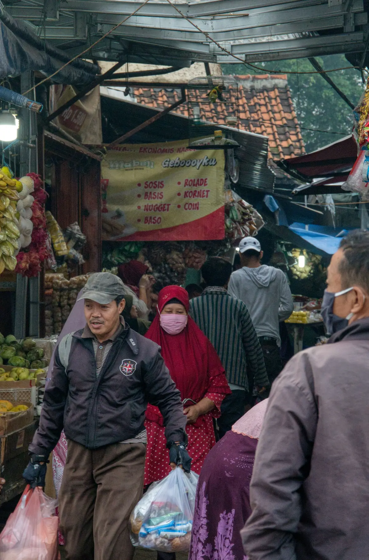 Orang-orang membawa tas belanja melalui pasar jalanan di Banten, Indonesia.